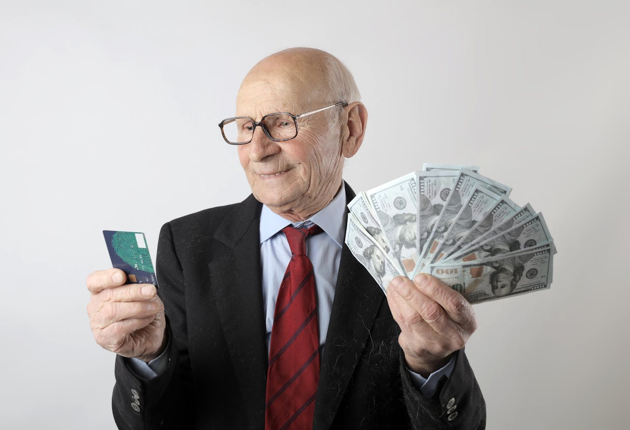 Crafting Captivating Headlines: Your awesome post title goes here Elderly man in a suit holding a credit card and US dollar bills, representing finance and wealth.